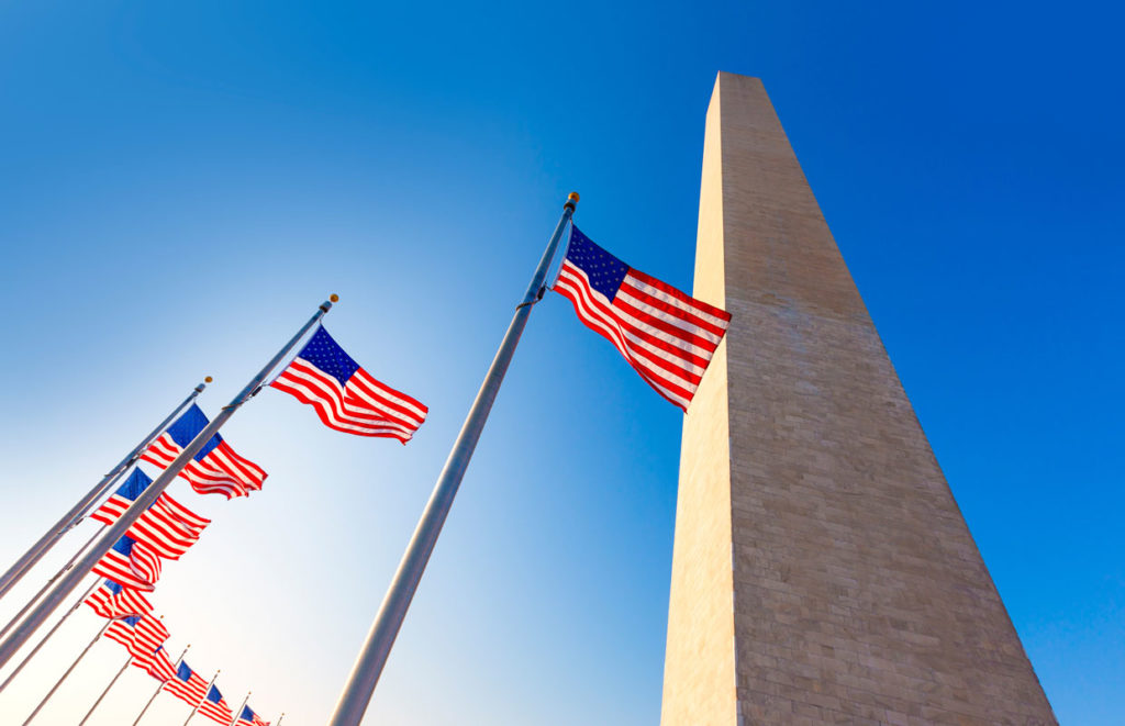 American flag in foreground with the Washington Monument behind—symbolic stop on Washington DC school trips focused on history and national identity.