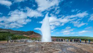 School group gathered round an erupting geysir in Iceland on a geography field trip
