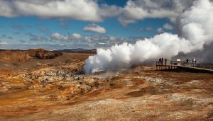 Tourists observe steaming geothermal vents at Hverir geothermal area in North Iceland — a key site for educational school tours exploring volcanic landscapes and geothermal energy.