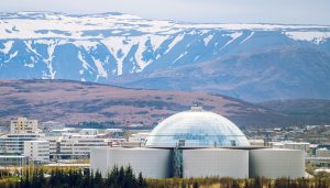 Aerial view of Perlan in Reykjavik, Iceland, with snow-capped mountains in the background — a key stop for school trips exploring Icelandic geography and natural sciences.