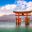 Iconic floating Torii gate of Itsukushima Shrine in Miyajima, Japan with calm water and mountain backdrop, popular destination for cultural and educational school trips.