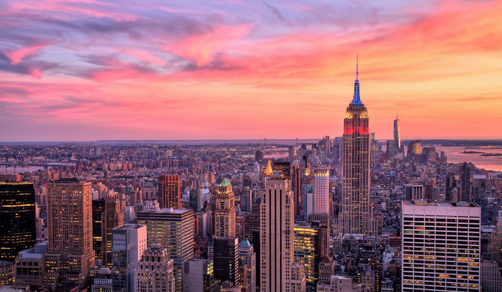 New York City skyline at sunset featuring the Empire State Building lit up, popular destination for educational school trips and cultural tours in the USA.