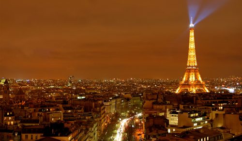 Paris Eiffel Tower lit up at night with spotlights on top