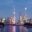 A twilight view of Shanghai's iconic skyline, featuring the illuminated Oriental Pearl Tower, the Shanghai World Financial Center, and the Shanghai Tower rising above the city’s vibrant financial district. The lights reflect off the Huangpu River, creating a colourful, modern urban scene.