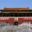The Tiananmen Gate in Beijing, China, featuring traditional Chinese architecture with a large portrait of Chairman Mao Zedong above the central entrance. Red banners with Chinese characters are displayed on either side, and visitors walk along the white stone pathway leading to the entrance.